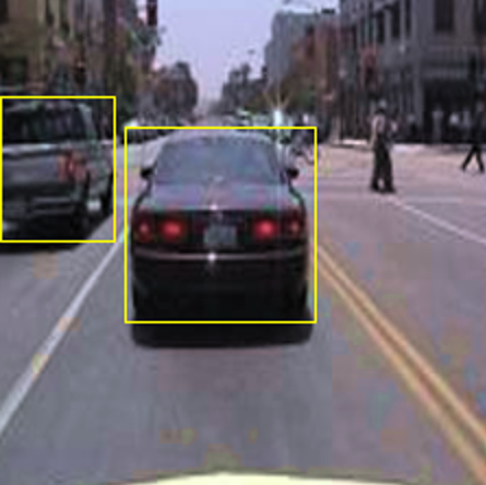 Image of traffic in a city with two cars, both highlighted by yellow bounding boxes